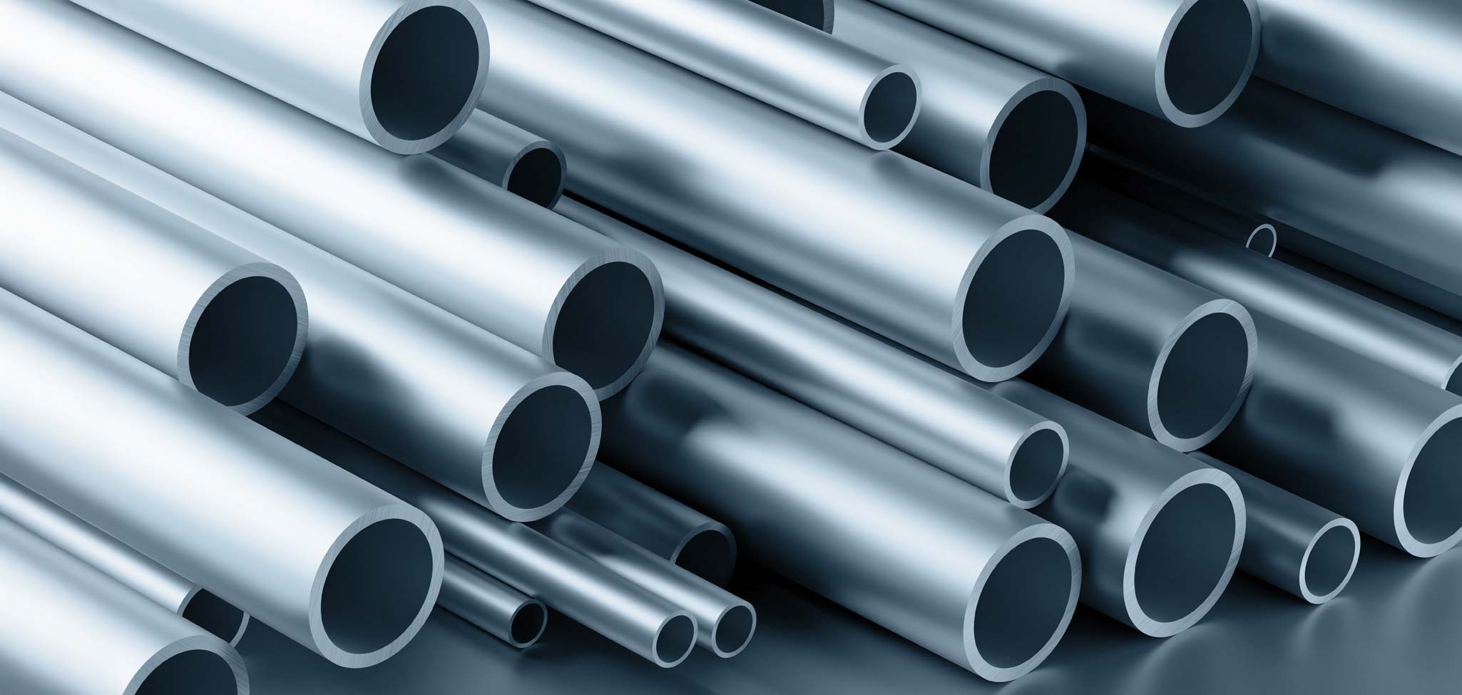 Das Bild zeigt eine Ansammlung glänzender, nebeneinander gestapelter Aluminiumrohre unterschiedlicher Durchmesser mit offen sichtbaren Rohrenden, die im Licht spiegeln.